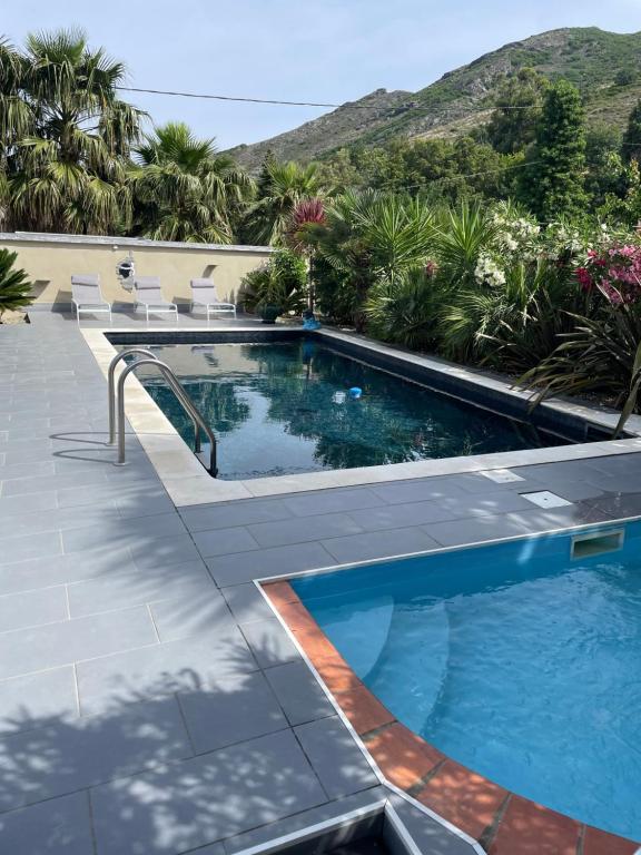 a swimming pool with chairs and a mountain in the background at Maison 9 couchages avec piscine et jardin au calme in Barbaggio
