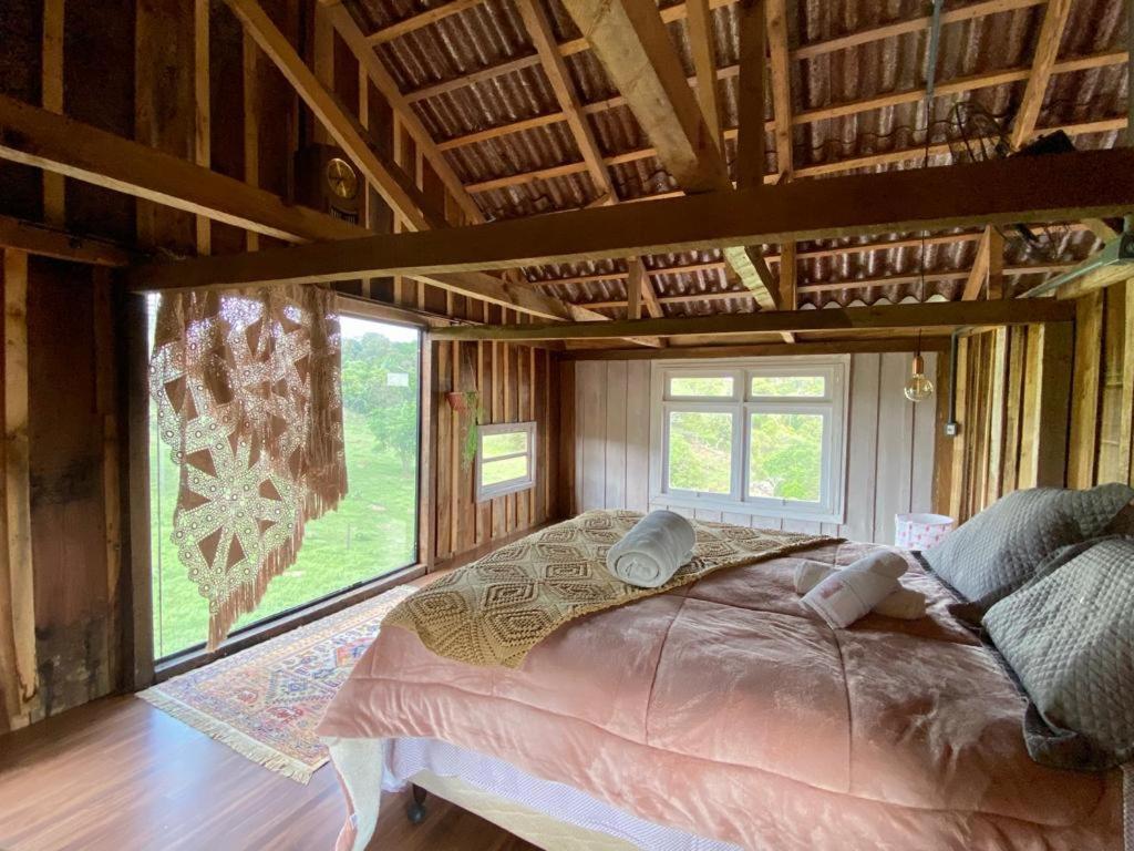 Una cama grande en una habitación con una ventana grande. en Celeiro Moderno em Guarapuava - Hospedagem Única para até 10 pessoas a 8km do centro, en Guarapuava