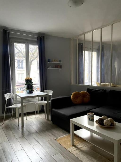 een woonkamer met een zwarte bank en tafels bij Apartment in the heart of Chinatown, Paris in Parijs
