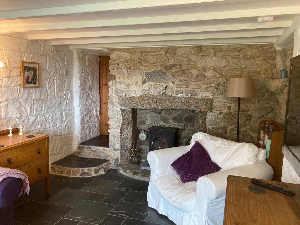 a living room with a stone fireplace with a white couch at Higher Trenear Farm B&B in Helston