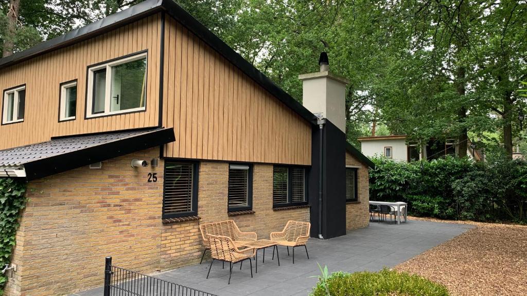 una casa con sillas y una mesa en un patio en 9 p bungalow in bossen bij Capfun Stoetenslagh en Rheezerveen