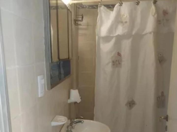 baño con ducha con cortina blanca en Amplio departamento en Godoy cruz en Godoy Cruz