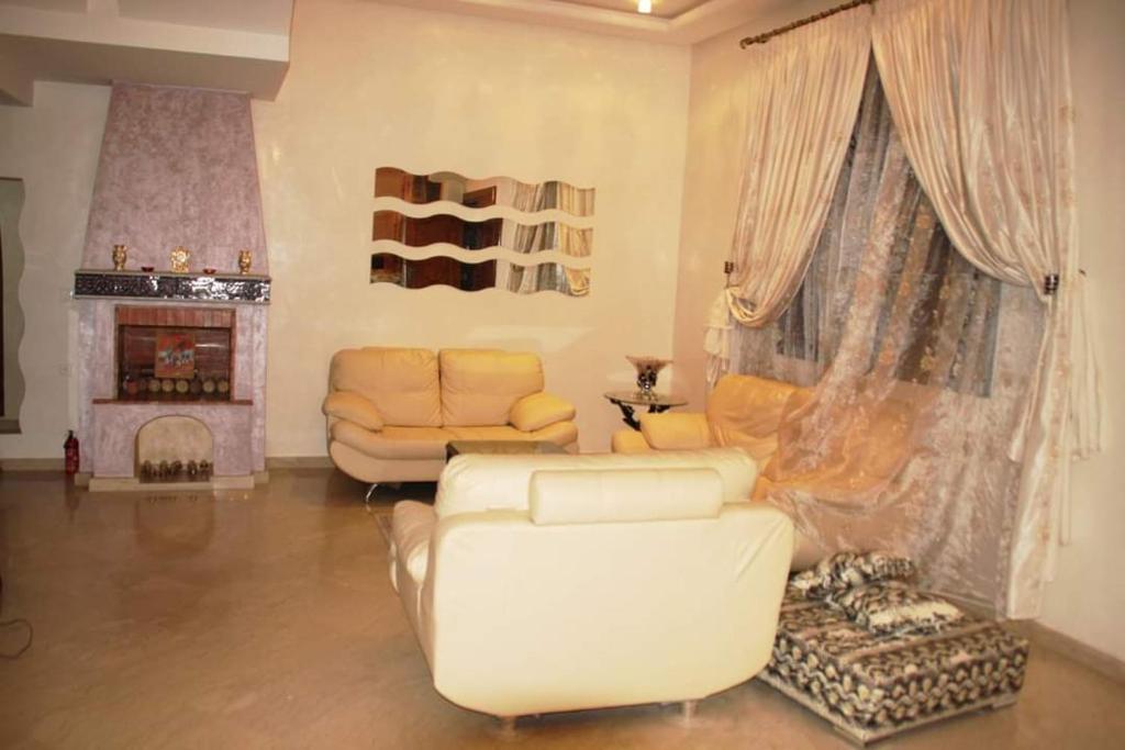sala de estar con muebles blancos y chimenea en Villa zohour, en Marrakech