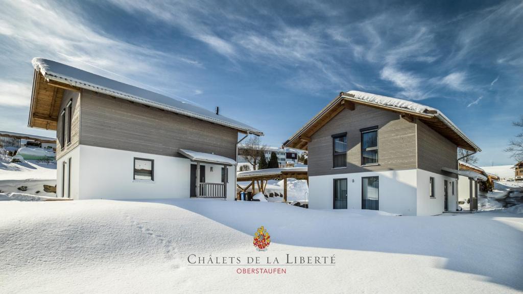 una casa nella neve accanto a un edificio di Châlets de la Liberté a Oberstaufen