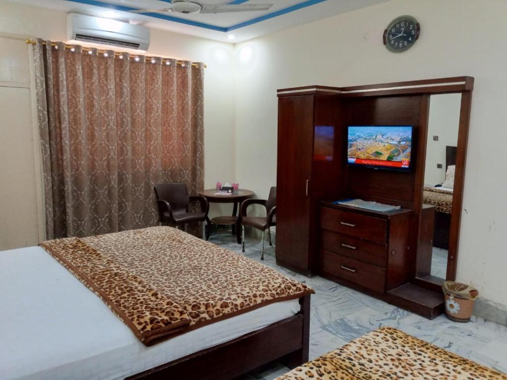 a hotel room with two beds and a tv and a table at Hotel Sky Inn Clifton in Karachi