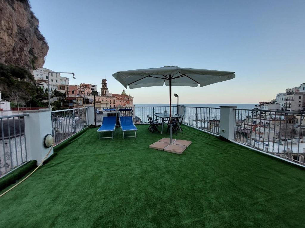 a balcony with a table and chairs and an umbrella at Blue's House in Atrani