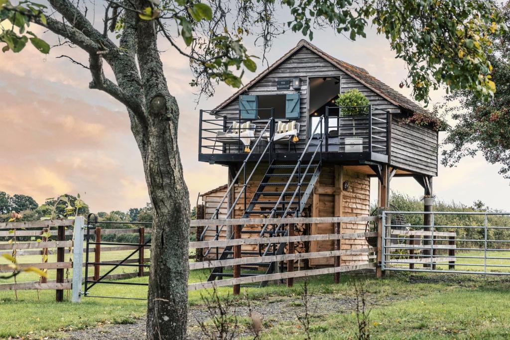 a tree house with a deck and stairs at The Treehouse at Humblebee Hall in Worcester