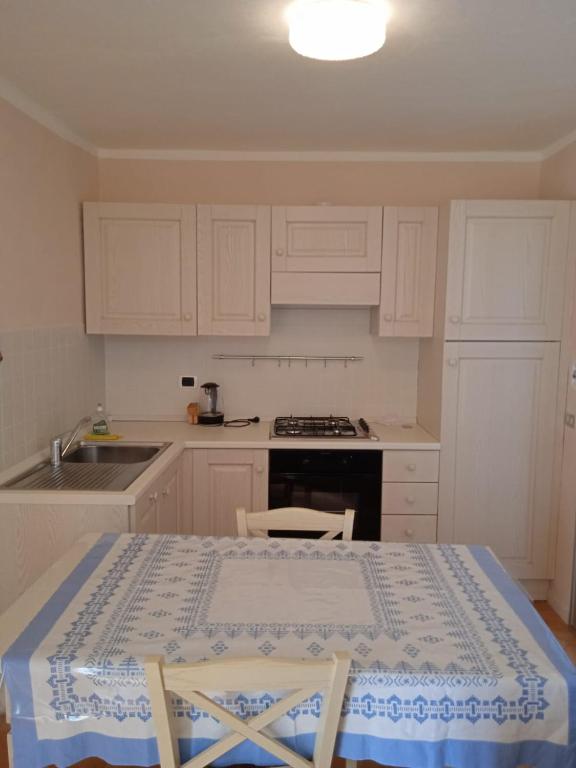 a kitchen with white cabinets and a table and a sink at Villa Imperia in Imperia