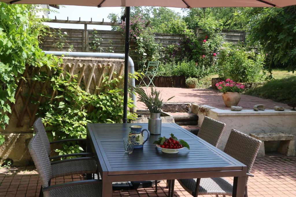une table bleue avec un bol de fraises sur une terrasse dans l'établissement Les Chenevières, à Culey