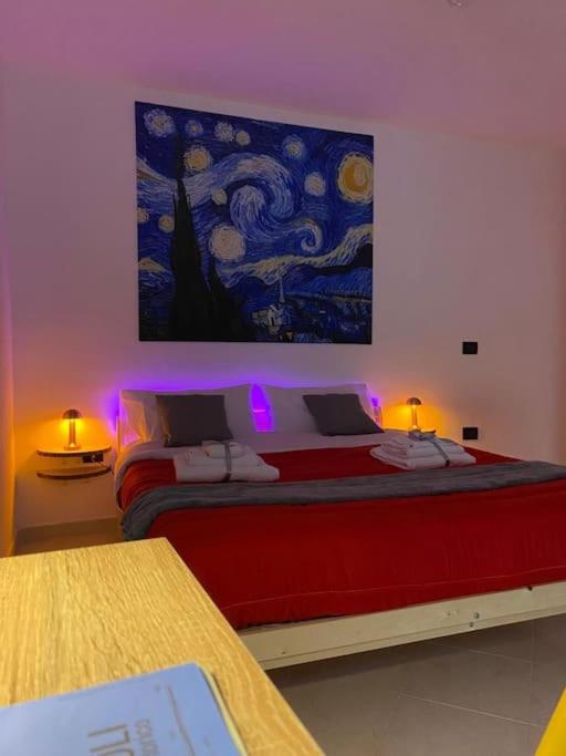 a bedroom with a red bed with a painting on the wall at Pontecorvo Naples Apartament in Naples