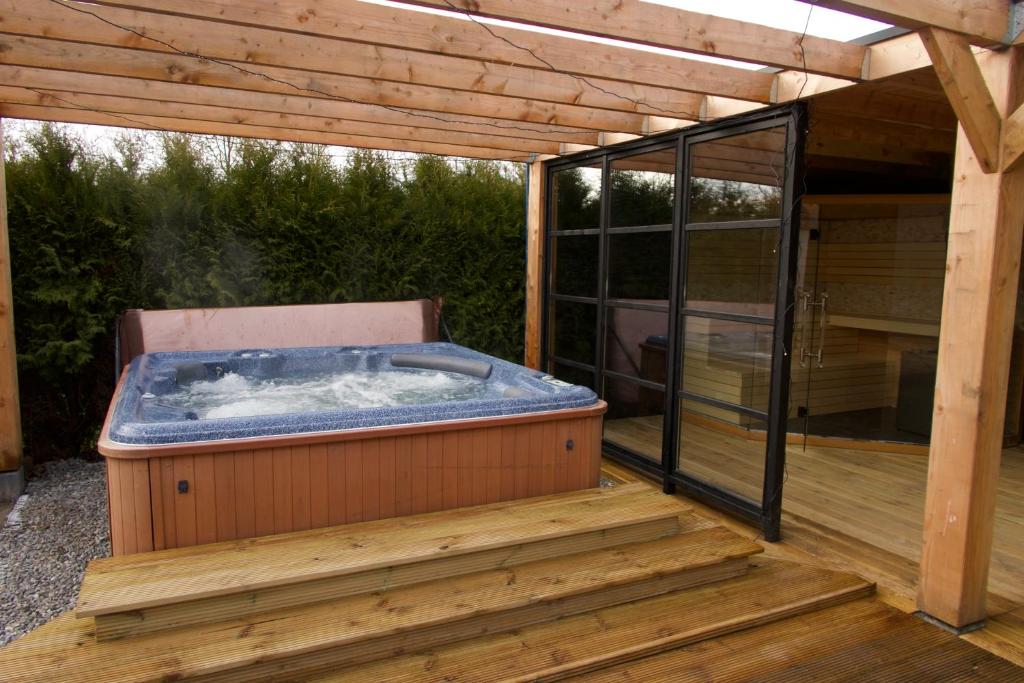 bañera de hidromasaje en una terraza de madera en Luxurious Family Villa with swimmingpool big garden and jacuzzi en Zeewolde
