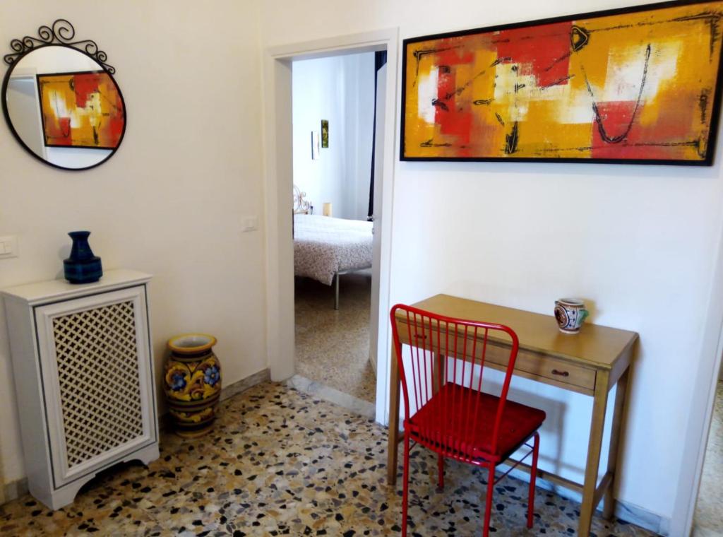 a room with a red chair and a desk and a painting at L'OZioRinco in Florence