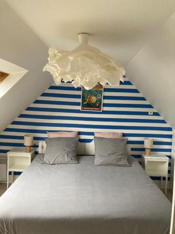 a bed with a blue and white striped wall at TY SEA in Morgat