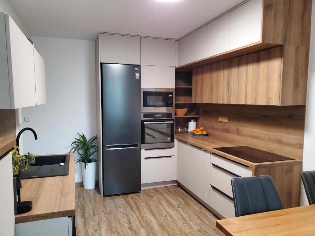 a kitchen with a black refrigerator and white cabinets at Nový apartman Eva in Jičín
