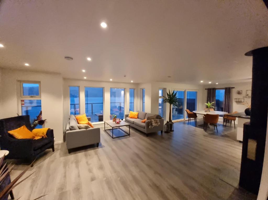 a large living room with couches and tables and windows at Kaldfjord Sea House in Tromsø