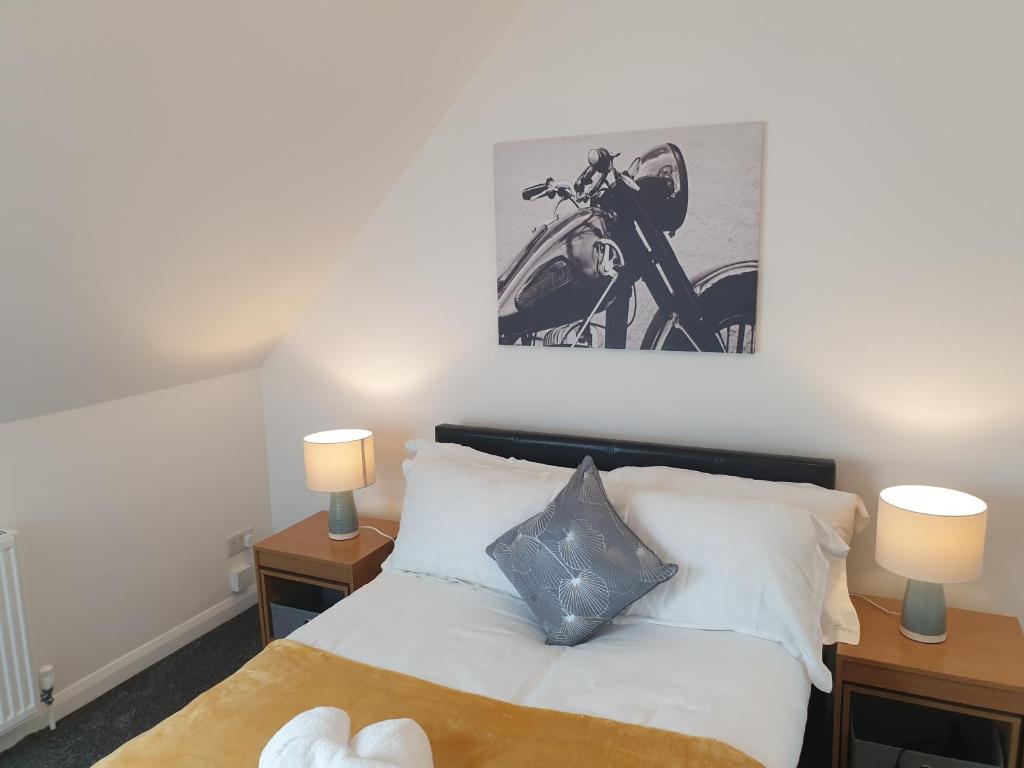 a bedroom with a bed with two lamps and a motorcycle on the wall at Marlow's Emerald 3 Bedroom House in Marlow