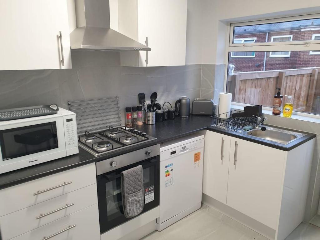 a kitchen with a microwave and a stove top oven at Chester le Street Amethyst 3 Bedroom House in Chester-le-Street