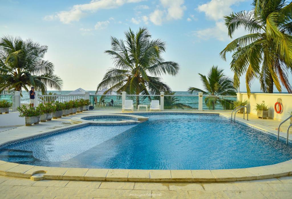 una gran piscina con palmeras y el océano en Magico Apartamento Frente al Mar 3 Habitaciones CV41, en Coveñas
