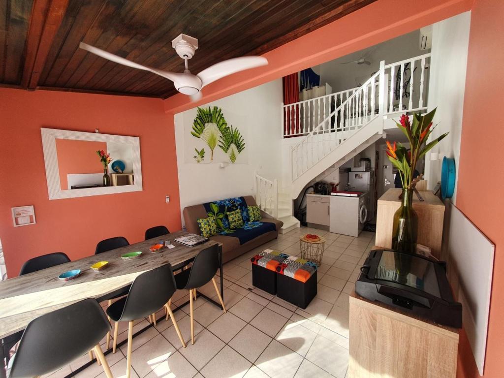 uma sala de estar com uma mesa e cadeiras e uma escadaria em appartement KER-EOL Sainte-Anne avec piscine em Sainte-Anne