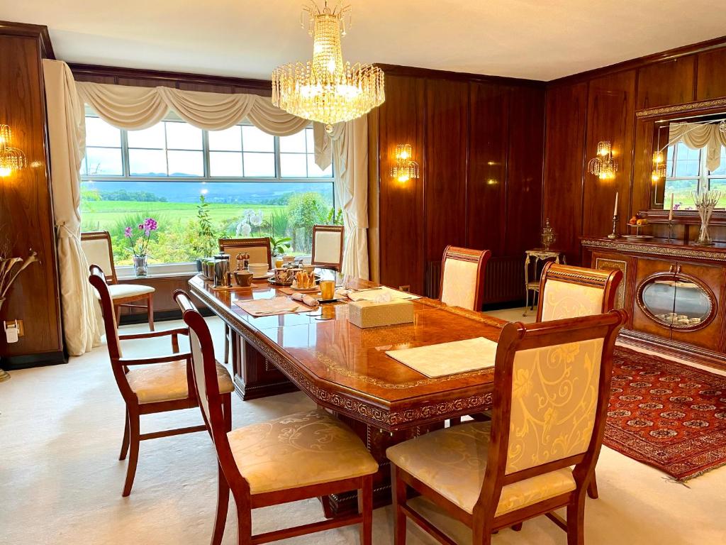 een eetkamer met een houten tafel en stoelen bij FINN VILLAGE - Loch Lomond Villa B&B with a Hot Tub in Glasgow