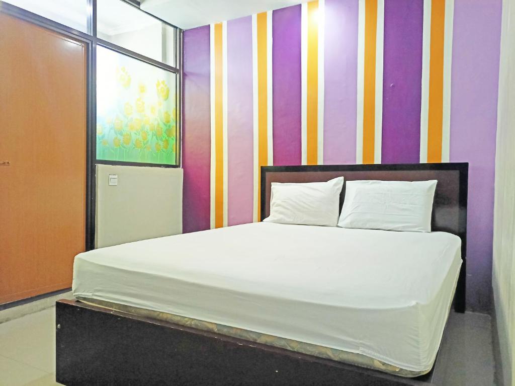 1 cama en una habitación con una pared colorida en OYO 92126 Hotel Syariah Sumber Mulya Nunukan en Nunukan