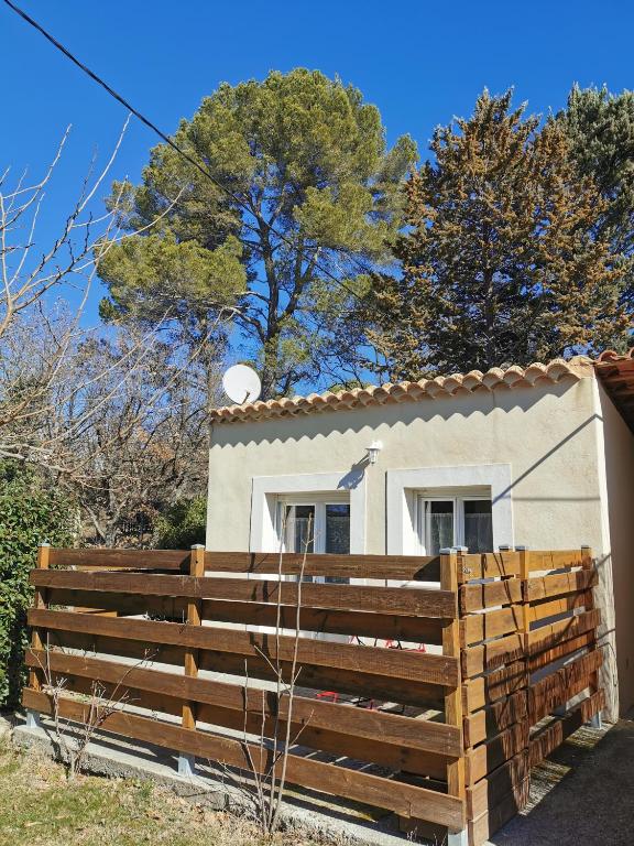 une maison avec une clôture en bois devant elle dans l'établissement Studio indépendant à 2 minutes du golf du Luberon, à Pierrevert