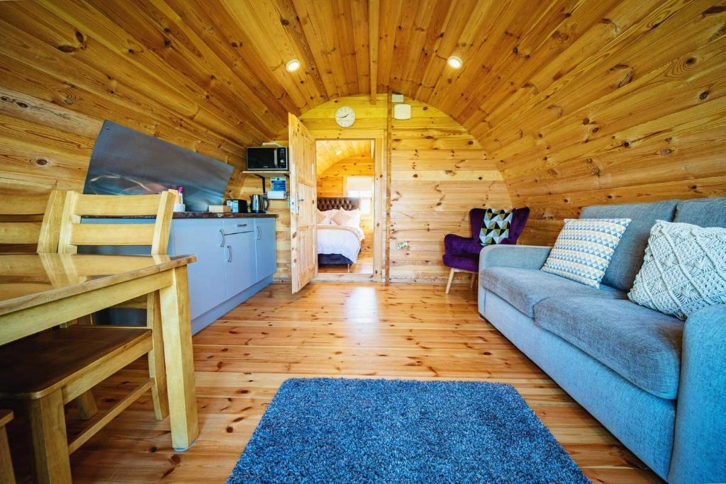 una sala de estar con un sofá azul en una cabaña de madera en Ceide Glamping, en Ballycastle