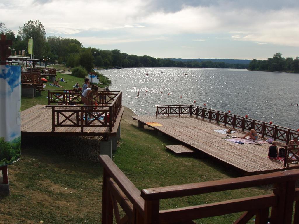 a dock on a lake with people sitting on the grass at SOBE KOD TETA MILKE in Veliko Gradište