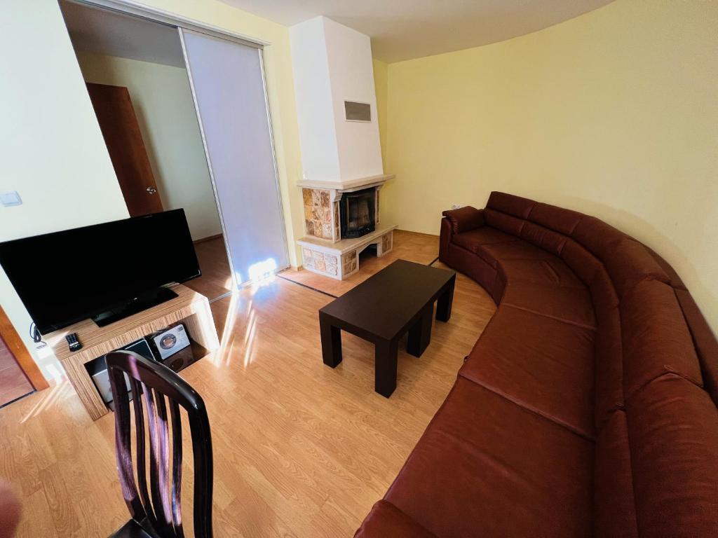 sala de estar con sofá y TV en Апартаменти Замъците, en Pamporovo