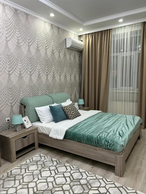 una camera da letto con un grande letto con lenzuola e cuscini verdi di Apartments GREEN PLAZA с видом на море ad Aqtau