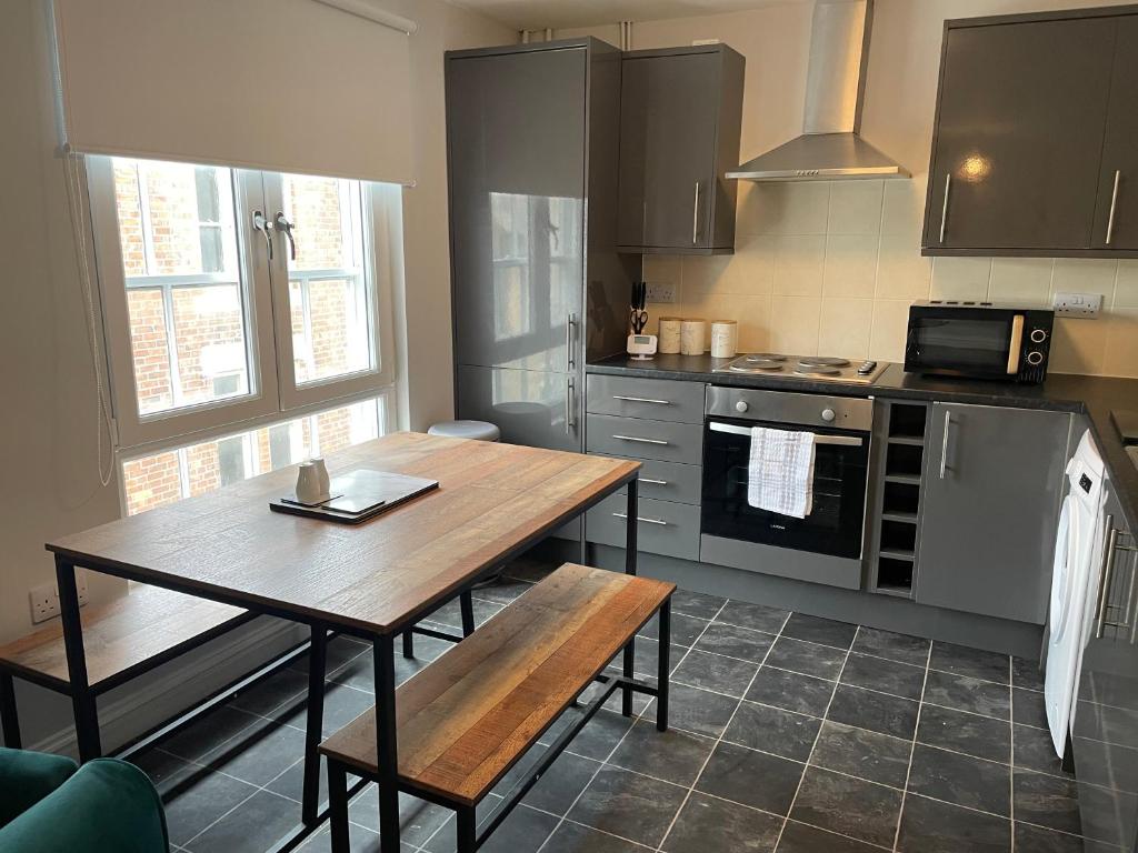uma cozinha com uma mesa de madeira e uma cozinha com um fogão em Cosy two bedroom apartment em Bishop Auckland