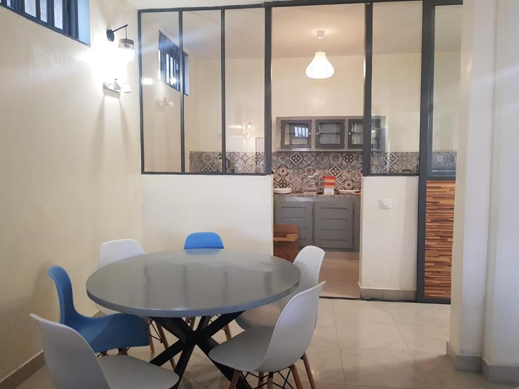 a dining room with a table and chairs and a kitchen at Bel appartement au centre ville de calavi BENIN in Abomey-Calavi
