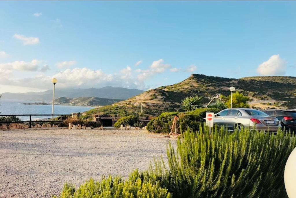 un estacionamiento con autos estacionados al lado del océano en Villetta a Schiera - Bosa Marina en Magomadas