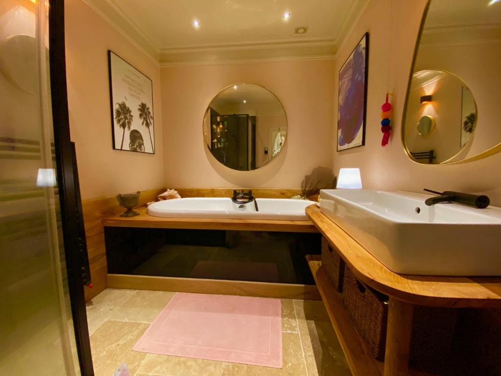 a bathroom with a tub and a sink and mirror at Art-Maison in Le Dorat