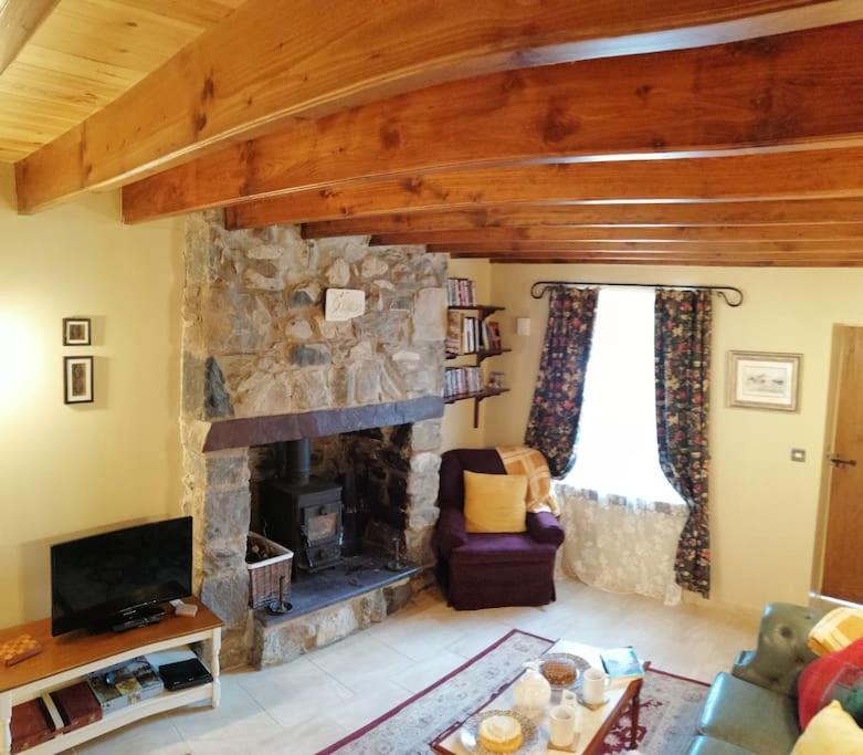 a living room with a stone fireplace and a couch at Lovely Stone Village cottage in Snowdonia in Waenfawr