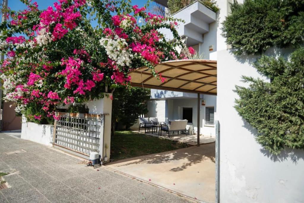 un jardín con flores rosas en un edificio blanco en Cozy Stay in Glyfada with WiFi, Garden, Parking, en Atenas