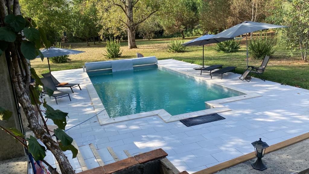 a pool with chairs and umbrellas in a yard at Chambres d'hôtes MoulinDT in Virazeil