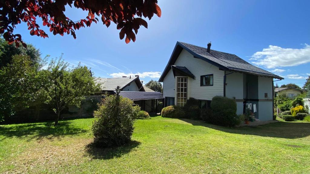 una casa blanca con un patio con una casa en Casa Las Violetas en San Carlos de Bariloche