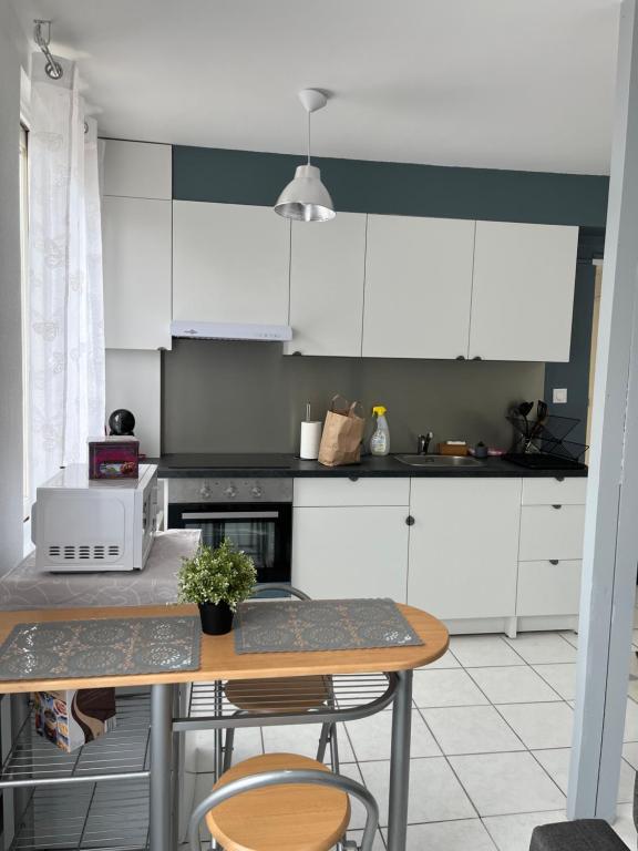 una cocina con armarios blancos y una mesa con sillas. en Belle maison, en Vigneux-sur-Seine
