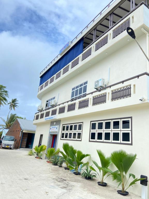 a white building with palm trees in front of it at Sunview Residence in Kaashidhoo