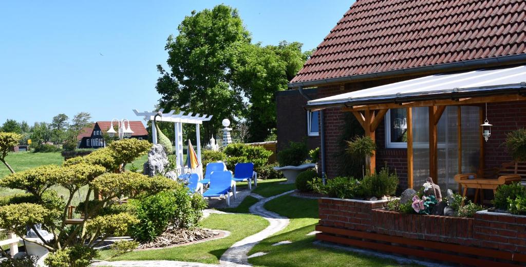 a garden with chairs and a house at Garni Hotel-Pension Holum in Neuharlingersiel