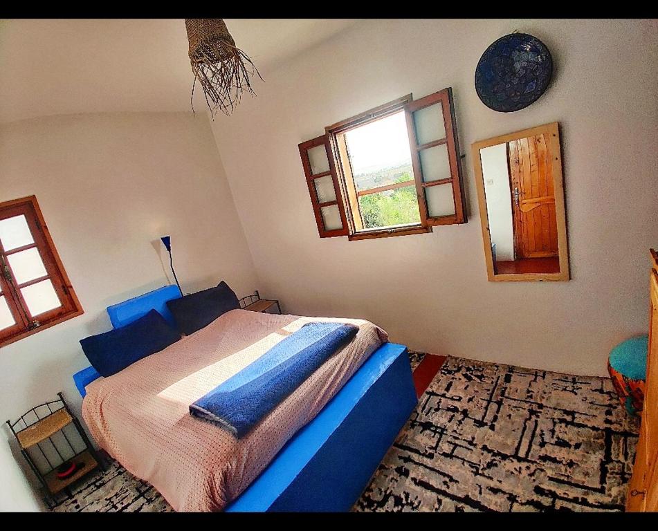 een slaapkamer met een bed in een kamer met ramen bij Hippie Chic Room 1 in Essaouira