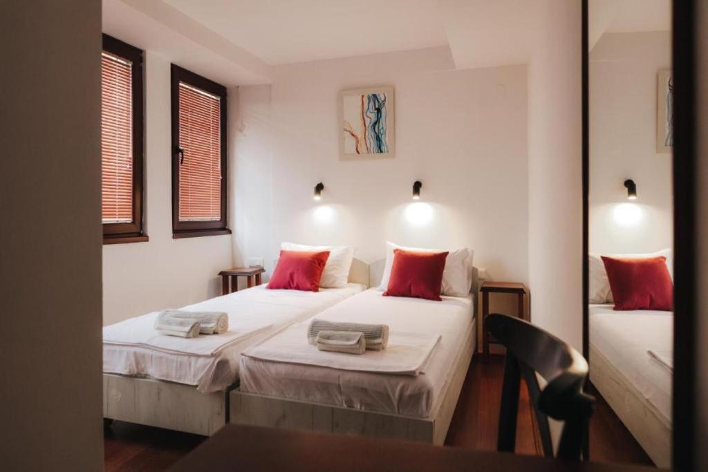 2 camas en una habitación pequeña con almohadas rojas en Hotel Castrum en Skopie