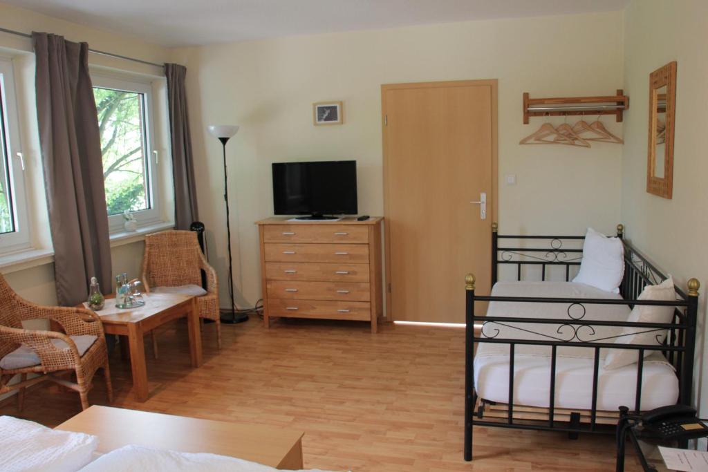Schlafzimmer mit einem Bett und einer Kommode mit einem TV in der Unterkunft Restaurant Fischbeck´s in Großenkneten