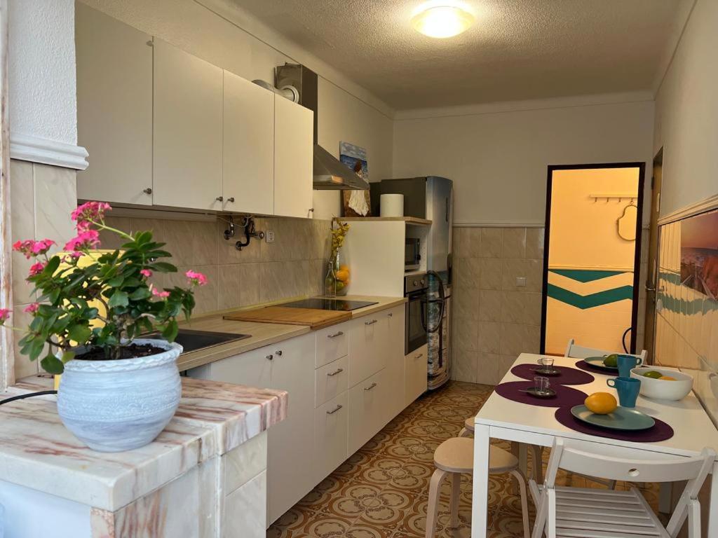 una cocina con armarios blancos y una mesa con una maceta. en Apartment Ericeira South, en Ericeira