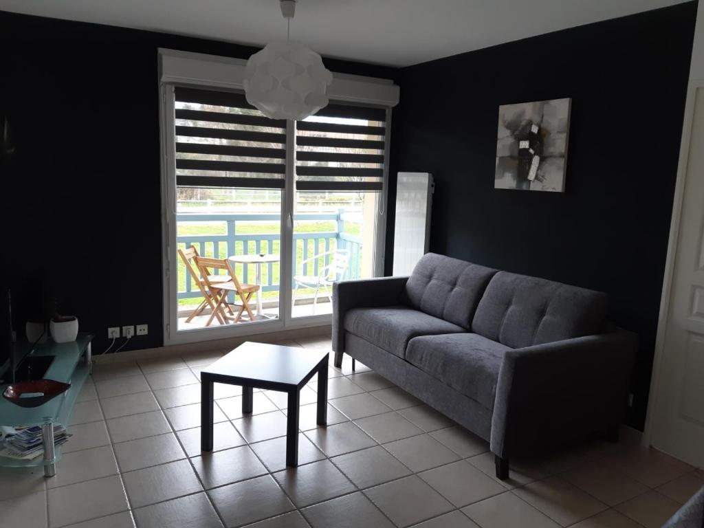 a living room with a couch and a table at L'appartement du parc vert marine in Houlgate