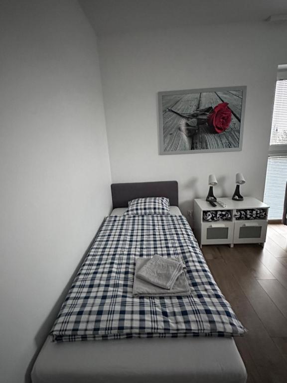 Una cama en una habitación con una manta a cuadros. en Pruszkowskie mieszkanko, en Pruszków