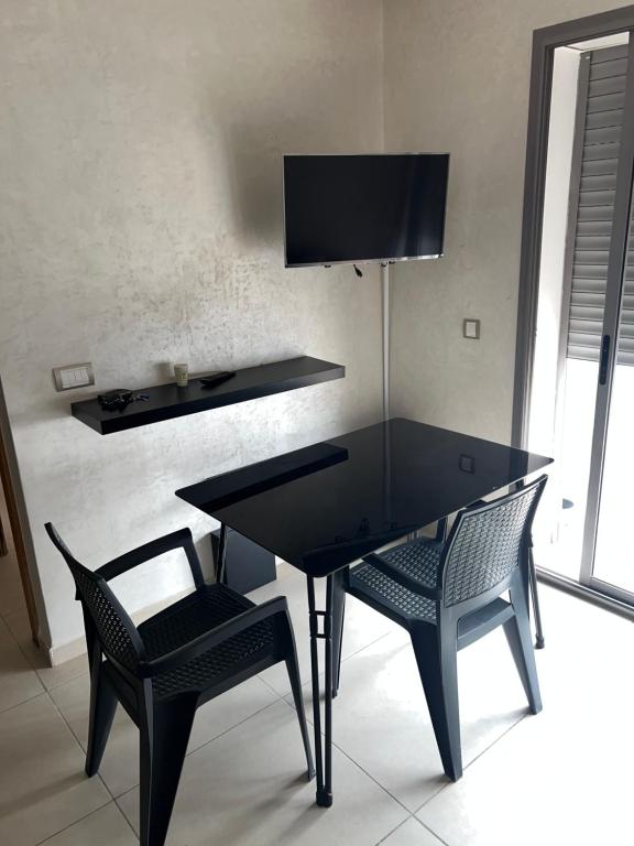 穆罕默迪耶的住宿－اقامة Mansbay，一张带两把椅子的黑桌和墙上的电视机