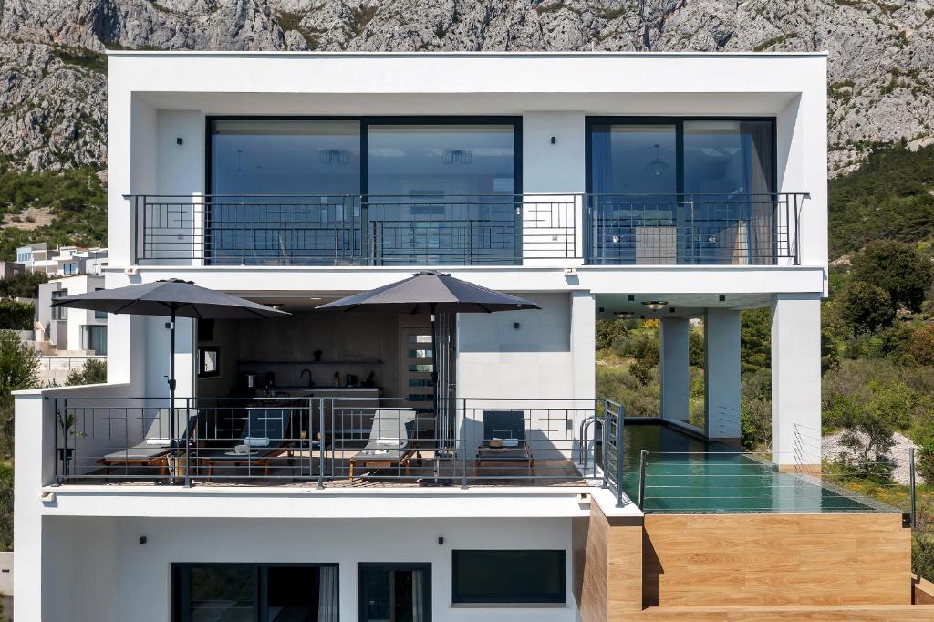 a large white house with a deck with umbrellas at Villa Teraco in Makarska
