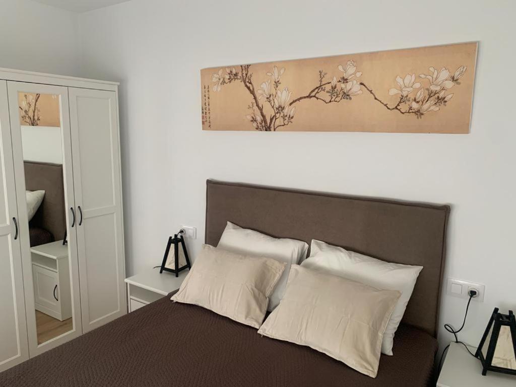 1 dormitorio con 1 cama grande con almohadas blancas en Fantástico piso con piscina y balcón en el Medano, en El Médano